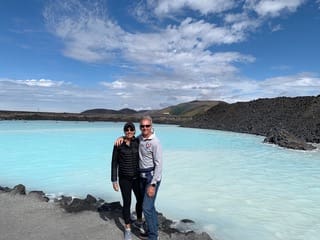 Two people standing in front of a body of water.